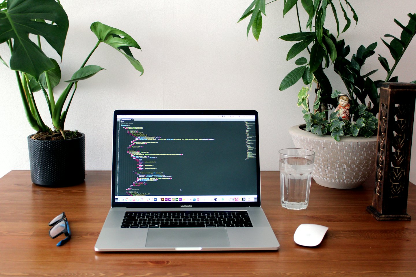 Laptop with colorful code on a wooden desk with plants.